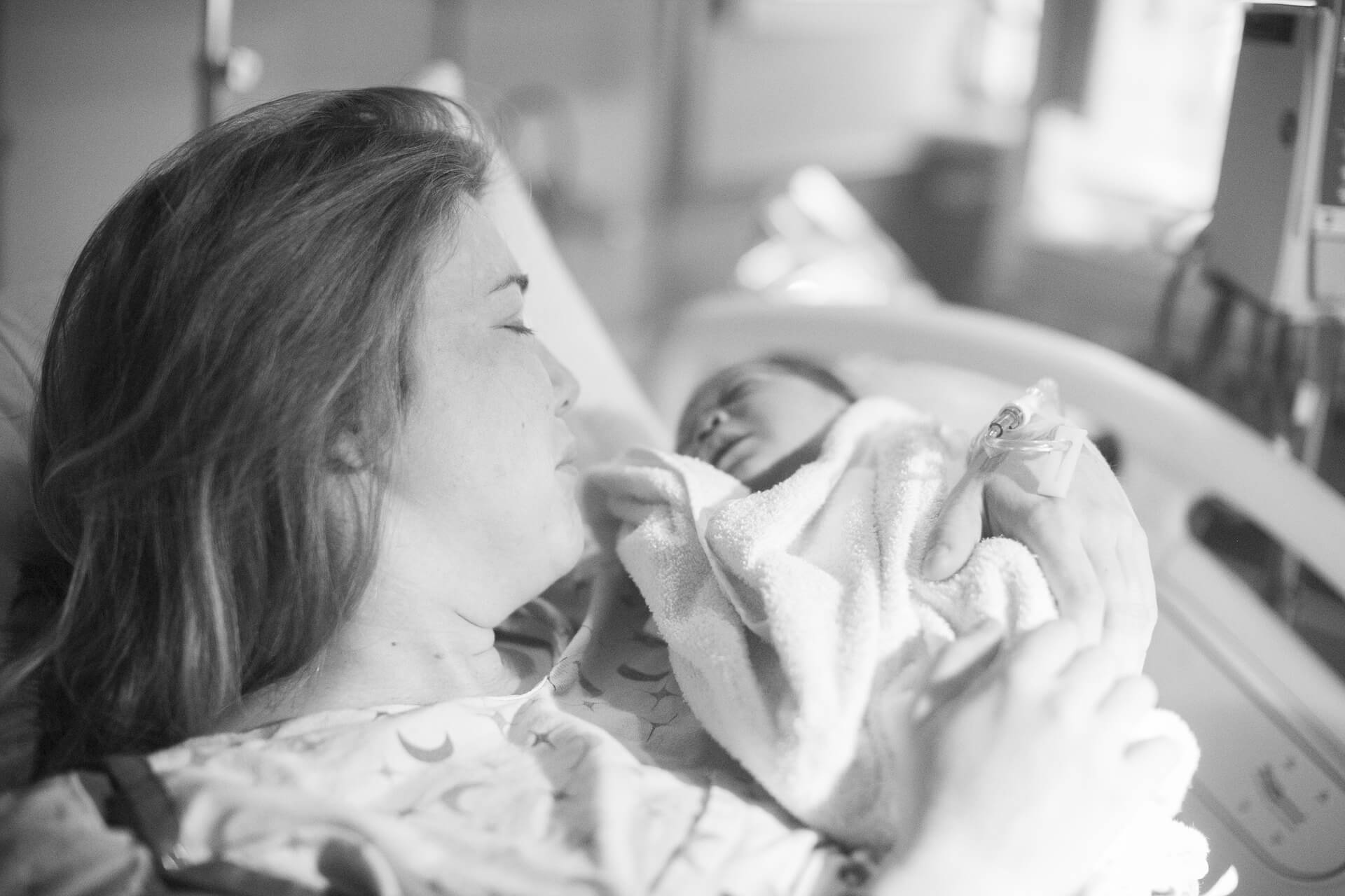 A woman holding a newborn in a hospital bed | B3PTco