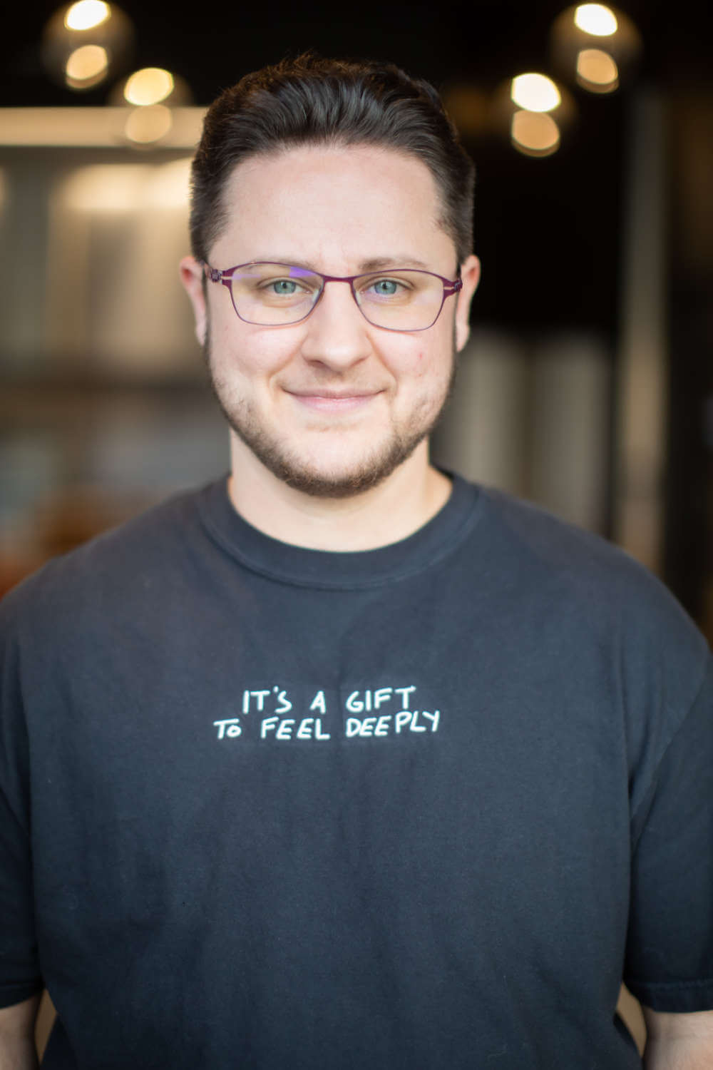 Headshot of gender-affirming physical therapist, Ken McGee. His shirt reads "It's a gift to feel deeply"
