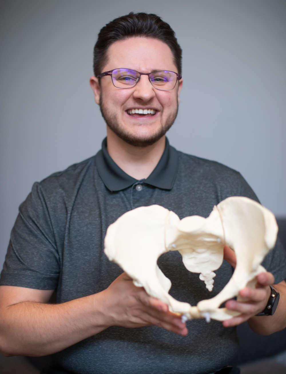 Photo of Ken McGee smiling and holding a pelvis model.